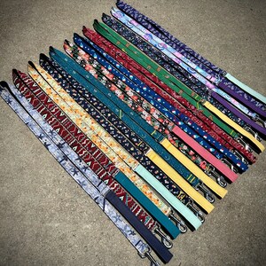 May include: A collection of 20 colorful dog leashes with various patterns, including floral, geometric, and paisley designs. The leashes are arranged in a fan shape, with the ends of the leashes pointing towards the bottom of the image.