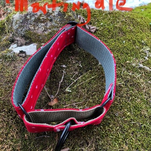 May include: Red dog collar with white polka dots and a gray fabric lining. The collar has a black metal D-ring.