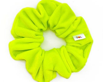 May include: A bright neon green scrunchie with a small white label that says "SOL" in black letters.