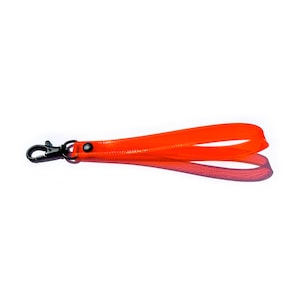 Op de afbeelding: Een feloranje sleutelhanger met een zwarte metalen sluiting.