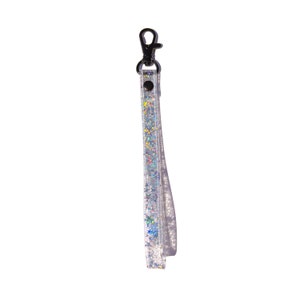Op de afbeelding: Een zilveren sleutelhanger met een zilveren glitterband en een zwarte metalen clip.