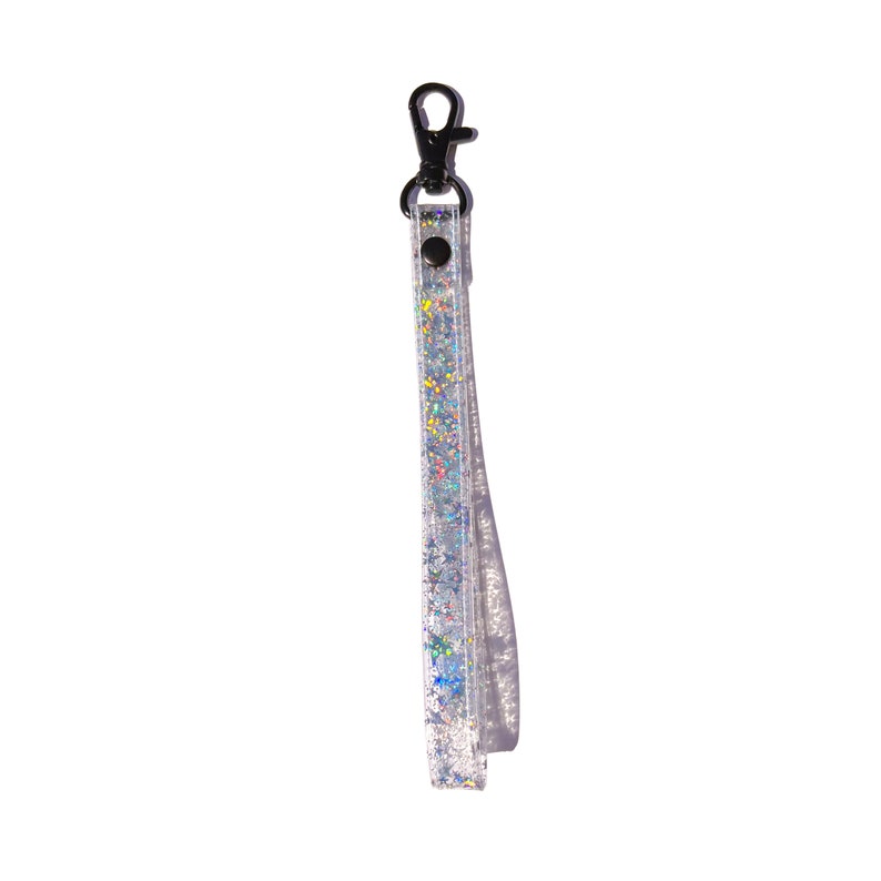 Op de afbeelding: Een zilveren sleutelhanger met een zilveren glitterband en een zwarte metalen clip.