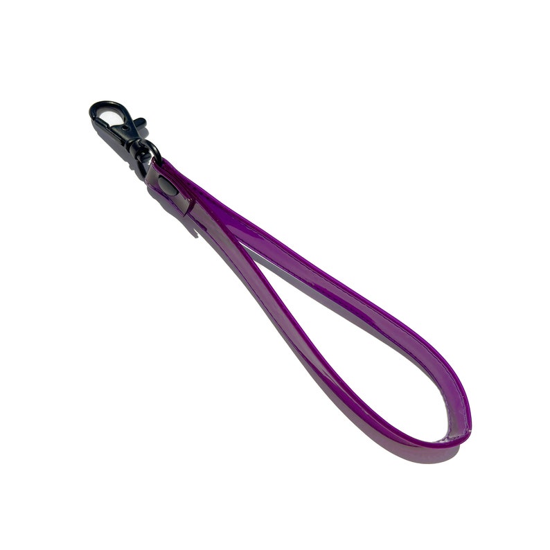 Op de afbeelding: Een paarse leren polsband met een zilveren metalen sluiting.