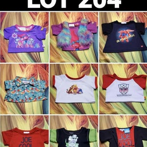 May include: A collection of children's t-shirts and tops, including a purple shirt with a Trolls graphic, a blue shirt with a Baymax graphic, and a red shirt with "JOE COOL" text. The image also includes a shirt with a Transformers logo.