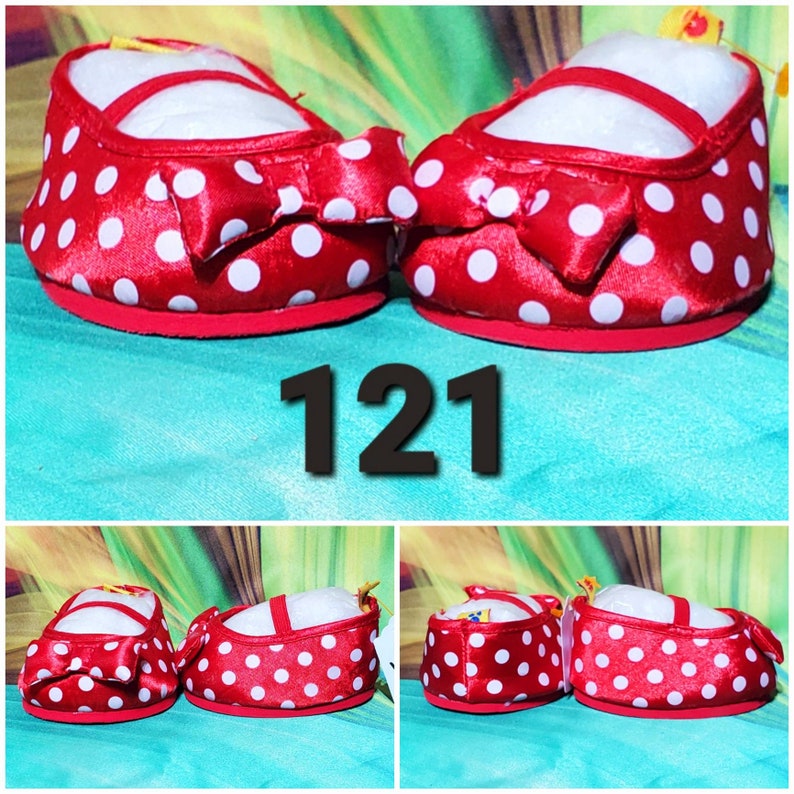 K&ouml;nnte beinhalten: Paar rote Babyschuhe mit wei&szlig;en Punkten und einer Schleife. Die Schuhe haben eine rote Sohle und einen Riemen &uuml;ber der Oberseite. Die Nummer "121" wird im Bild angezeigt.