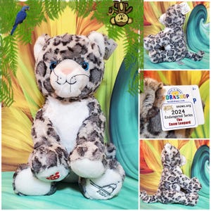 May include: A Build-A-Bear Workshop plush snow leopard, part of the 2024 Endangered Series. The stuffed animal has a white belly, gray spots, and blue eyes. The tag reads "The Snow Leopard".