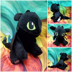 May include: Black plush toy dragon with green eyes. The dragon is sitting on a colorful background.