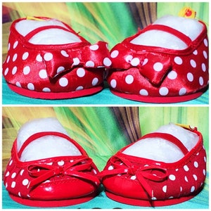 K&ouml;nnte beinhalten: Ein Paar rote Babyschuhe mit wei&szlig;en Tupfen. Jeder Schuh hat eine rote Schleife und einen Riemen &uuml;ber dem Oberteil. Die Sohlen sind rot und die Schuhe sind mit wei&szlig;em Papier gef&uuml;llt.