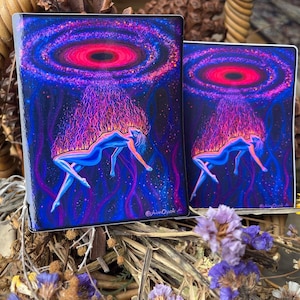 May include: Two rectangular stickers featuring a vibrant cosmic illustration of a figure floating in space. The artwork displays a bright pink and purple nebula above a blue-toned figure with flowing hair, set against a dark starry background.