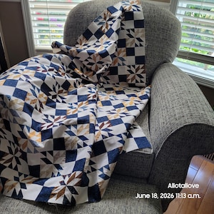 May include: A quilt featuring a repeating star pattern in navy blue, white, and tan. The fabric displays a geometric design with alternating solid navy blue squares and star-shaped blocks. The text Allotallove June 18, 2026 11:13 a.m. is visible.