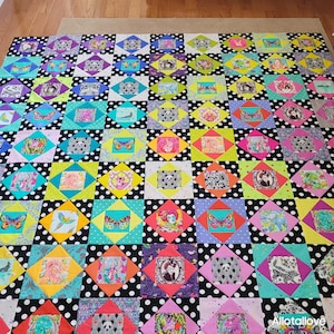 May include: A patchwork quilt featuring a grid of square blocks with a black and white polka dot fabric alternating with colourful squares. Each colourful square displays a unique graphic print, including butterflies, animals, and portraits.