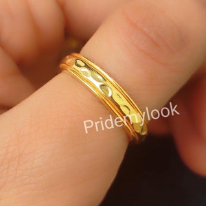 May include: A gold ring with a textured band and a smooth interior. The ring is worn on a finger. The text "Pridemylook" is visible on the ring. The ring is a jewelry item.