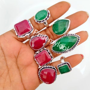 Könnte beinhalten: Ein Set aus neun Silberringen mit roten und grünen Edelsteinen. Die Ringe zeigen verschiedene Stile und Größen von Edelsteinen, darunter quadratische, ovale und runde Formen.