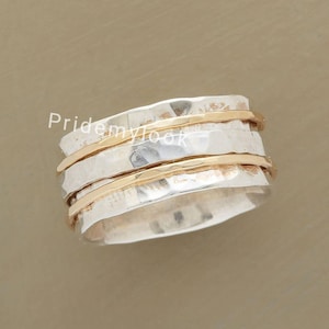 May include: A silver and gold spinning ring with a hammered texture. The ring has two thin gold bands.