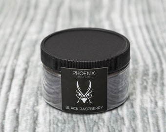 May include: A black plastic jar with a black lid containing black raspberry pigment powder. The label reads "PHOENIX PIGMENT POWDER" and "BLACK RASPBERRY".