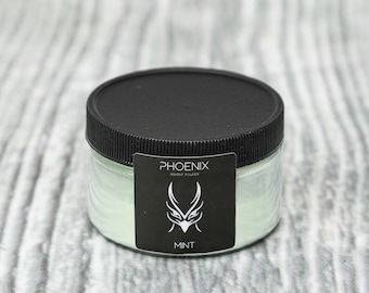 May include: A round jar of green pigment powder with a black lid. The label reads "PHOENIX PIGMENT POWDER" and "MINT".