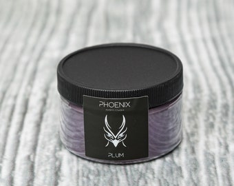 May include: A black jar with a black lid containing purple pigment powder. The label reads "PHOENIX ACRYLIC POWDER" and "PLUM".