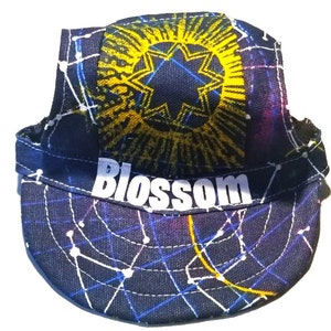 May include: A black, blue, and yellow cycling cap with a starburst design and the word "Blossom" printed on the front.