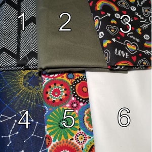 May include: Six fabric swatches with numbers 1 through 6.  Swatch 1 is black with white chevron arrows. Swatch 2 is olive green. Swatch 3 is black with rainbow, hearts, and the word "love" in white. Swatch 4 is navy blue with yellow stars and white constellations. Swatch 5 is white with colorful mandala designs. Swatch 6 is white.