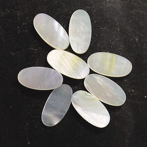 Può includere: Otto cabochon ovali in madreperla iridescente, disposti a cerchio. I cabochon hanno una lucentezza perlacea con variazioni di colore dal bianco al giallo pallido. Ideali per la creazione di gioielli.