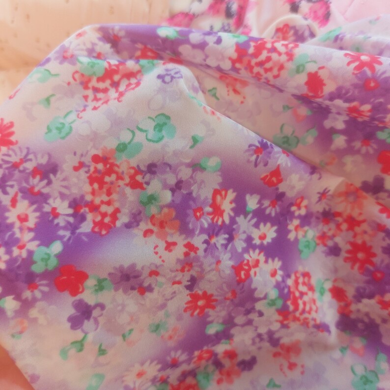 Puede incluir: Primer plano de una tela p&uacute;rpura y blanca con un patr&oacute;n floral. La tela es transparente y tiene un tacto suave y delicado.