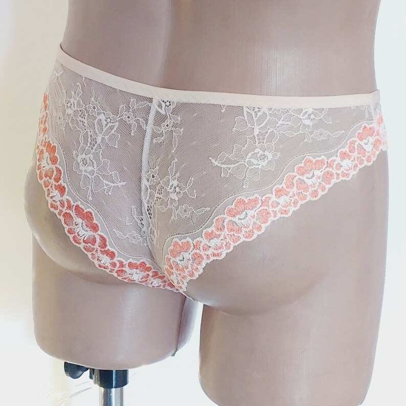 Puede incluir: Ropa interior de encaje blanco con ribete floral de color melocot&oacute;n.
