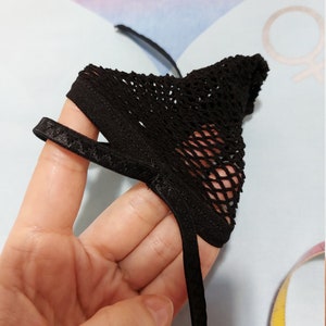 Puede incluir: Lencer&iacute;a de malla negra con una banda el&aacute;stica negra. La lencer&iacute;a se sostiene en una mano.