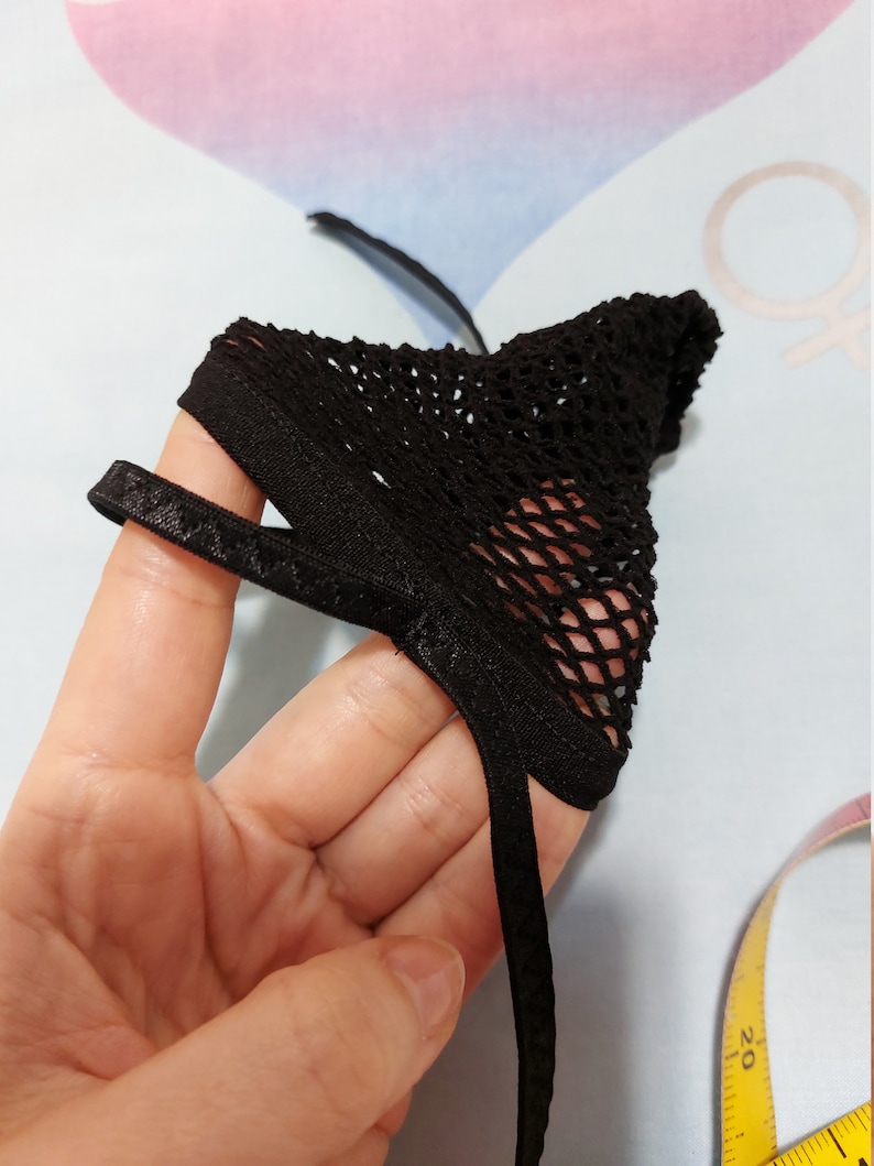 Puede incluir: Lencer&iacute;a de malla negra con una banda el&aacute;stica negra. La lencer&iacute;a se sostiene en una mano.