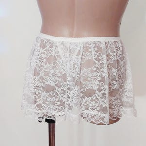 Puede incluir: B&oacute;xer de encaje blanco con un delicado patr&oacute;n floral. La parte inferior tiene una banda el&aacute;stica ancha y un borde festoneado.