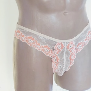 Puede incluir: Ropa interior de encaje blanco con bordado floral de color melocot&oacute;n.