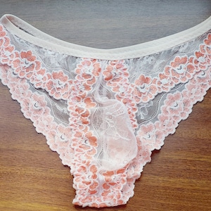 Puede incluir: Ropa interior de encaje blanco con un estampado floral melocot&oacute;n.