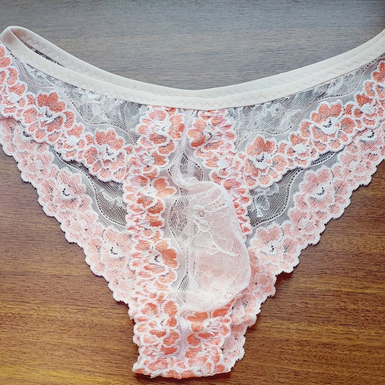 Puede incluir: Ropa interior de encaje blanco con un estampado floral melocot&oacute;n.