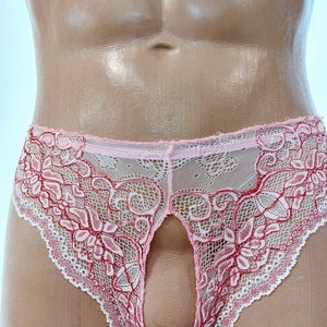 May include: Pink and white lace underwear with a floral design. The underwear has a keyhole opening in the front. The edges are scalloped.