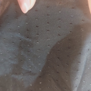 Puede incluir: Primer plano de una tela negra con un patr&oacute;n texturizado de puntos. La tela tiene una superficie lisa y ligeramente brillante.