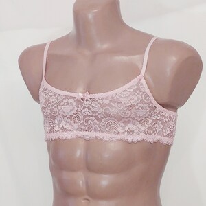 May include: A pink lace bralette with adjustable straps. The bralette features a delicate floral pattern and a bow detail in the centre.