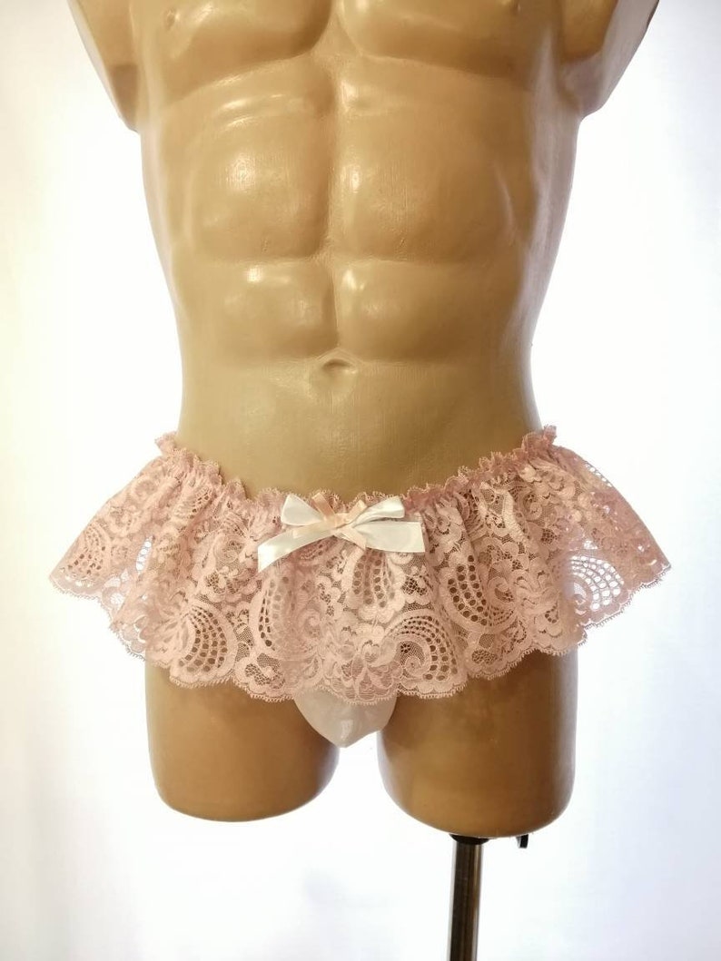 Pu&ograve; includere: Un lingerie in pizzo rosa con un fiocco bianco. Il pizzo &egrave; delicato e presenta un motivo floreale. Il lingerie &egrave; su un manichino.