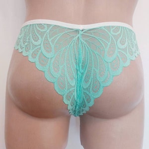 May include: Mint green lace underwear with a white waistband. The lace has a delicate, floral pattern.