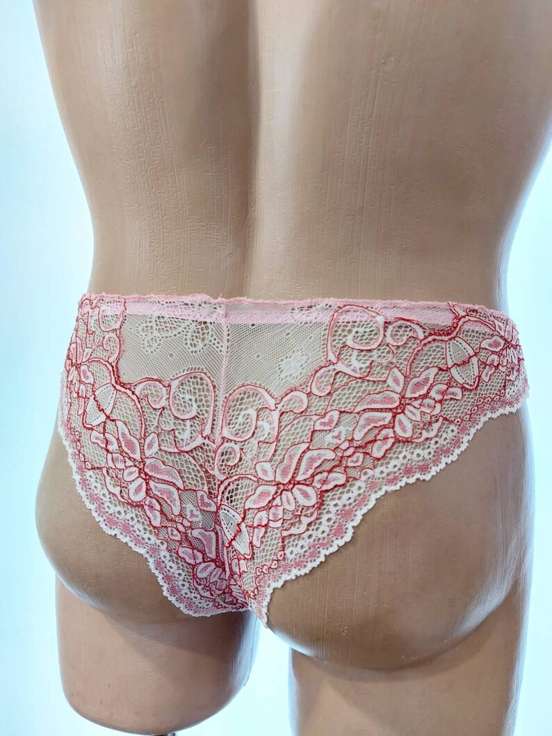 May include: Pink and white lace underwear with a floral design. The delicate lingerie features a scalloped edge and a sheer appearance. The underwear is displayed on a mannequin.