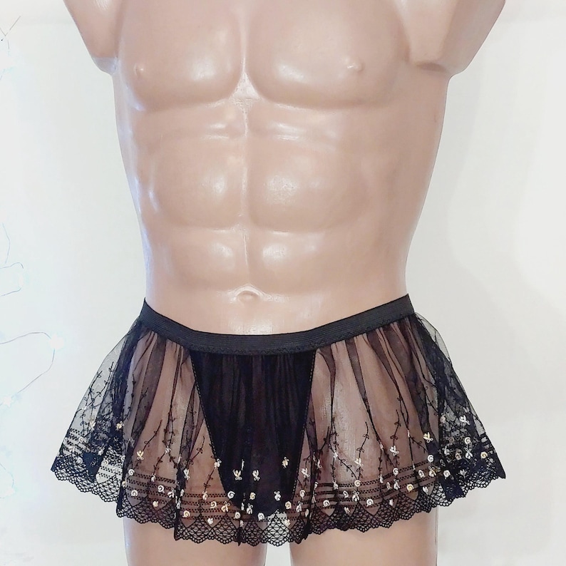May include: Black sheer mini skirt with delicate floral embroidery and lace trim. The skirt features a black elastic waistband and a layered design, creating a flowing, lightweight appearance. The skirt is designed for a comfortable fit.