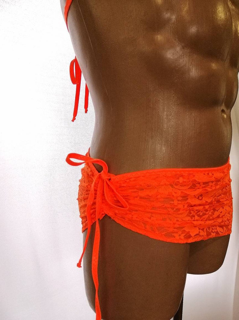 May include: Orange lace bikini bottom with a tie at the side. The bottom is made of a sheer fabric with a floral pattern.