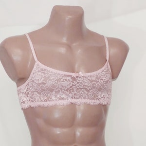 May include: A pink lace bralette with adjustable straps. The bralette features a delicate floral pattern and a bow in the centre.