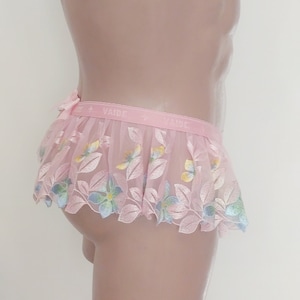May include: Pink floral lace underwear with a ruffled hem and the word "VAJDE" printed on the waistband.