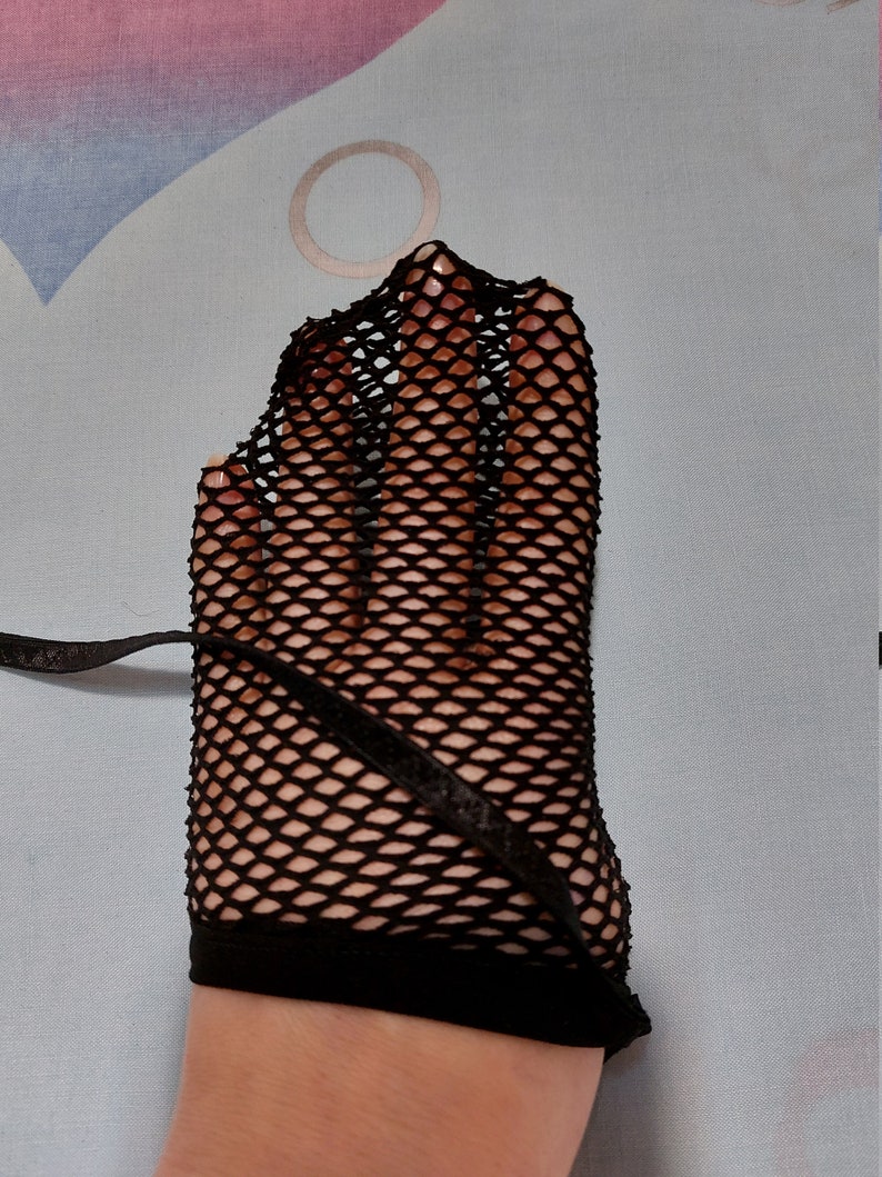 Puede incluir: Guantes sin dedos de rejilla negra con un lazo negro.