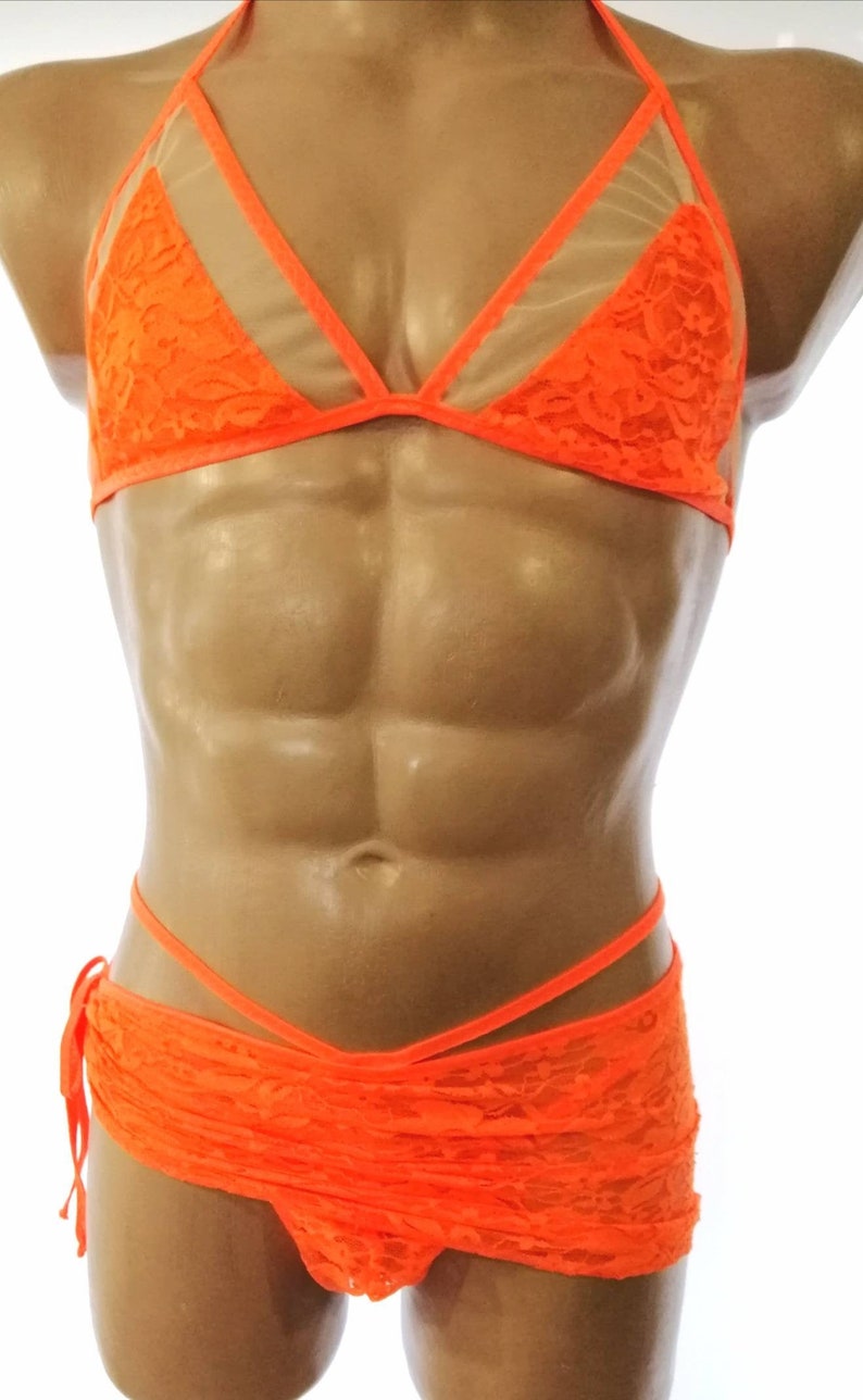 May include: Orange lace lingerie set with a halter top and a skirt. The top has a sheer mesh panel in the center. The skirt has a wrap-around design and ties at the side.