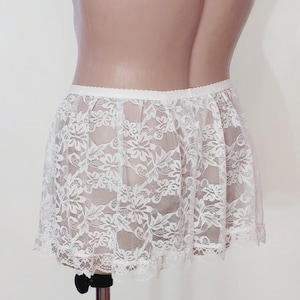 Puede incluir: Falda de encaje blanca con un delicado patr&oacute;n floral. La falda es transparente y tiene un dobladillo con volantes.