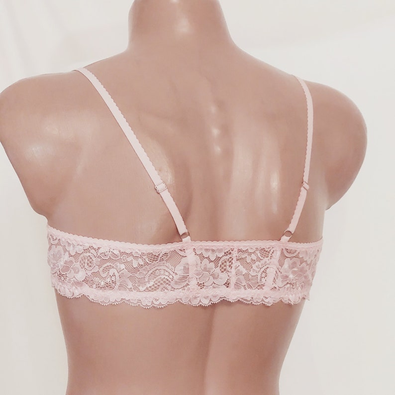 May include: A pink lace bralette with adjustable straps. The bralette is made of delicate lace and has a soft, feminine look.