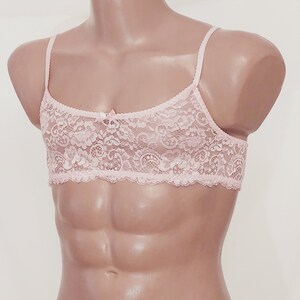 May include: A pink lace bralette with adjustable straps. The bralette is made of delicate lace and has a bow in the centre.