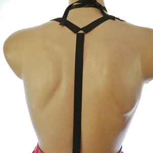 Puede incluir: Tirantes negros con un detalle de cinta en el cuello. Los tirantes est&aacute;n unidos a una falda de cuadros rojos y negros.