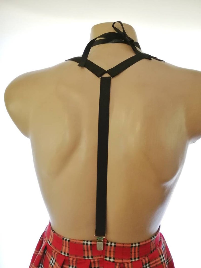 Puede incluir: Tirantes negros con un detalle de cinta en el cuello. Los tirantes est&aacute;n unidos a una falda de cuadros rojos y negros.