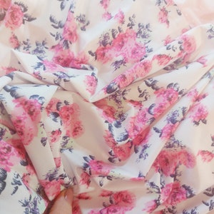 Puede incluir: Tela blanca con un estampado floral rosa y morado. La tela est&aacute; arrugada y tiene una textura suave y fluida.